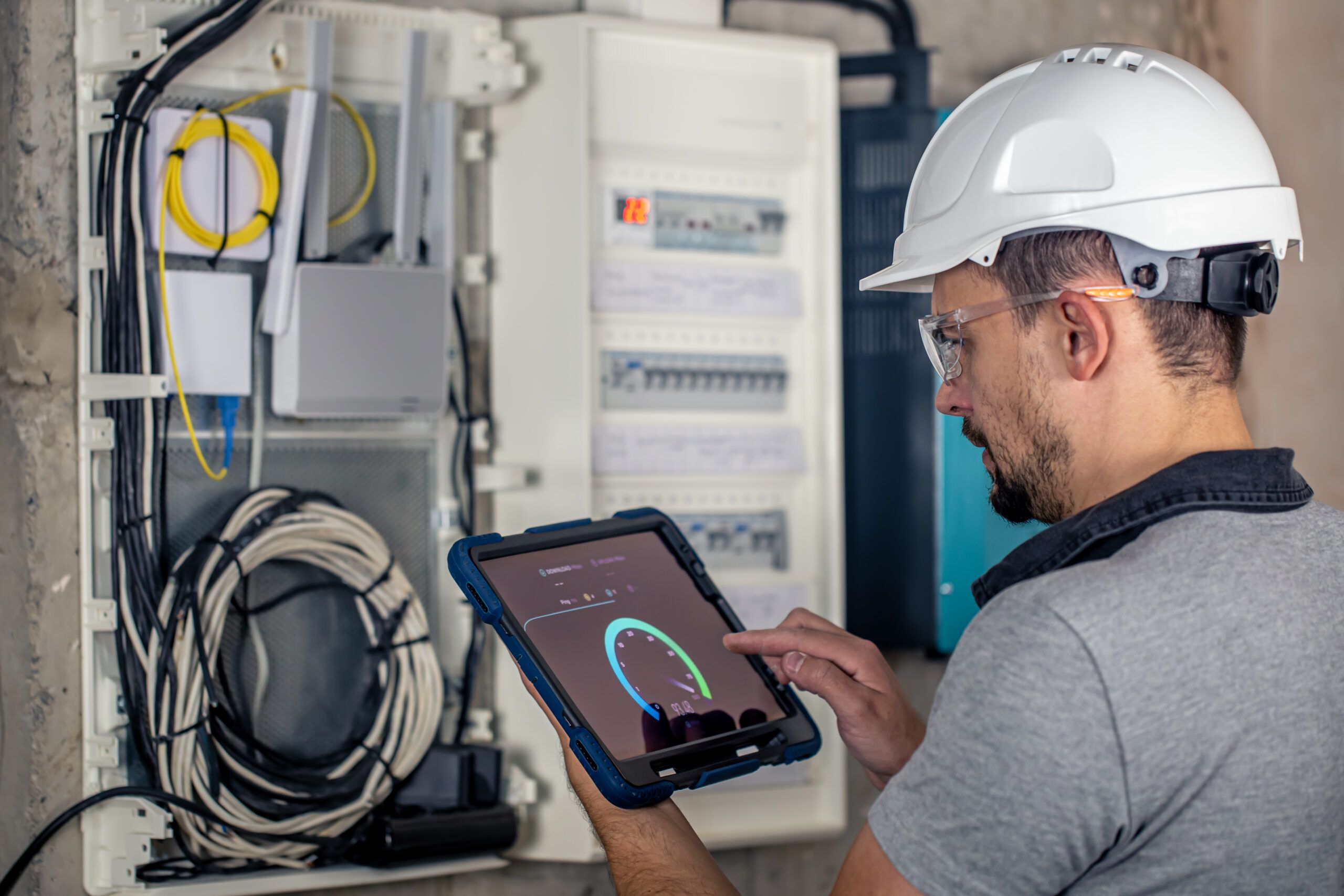 man-electrical-technician-working-switchboard-with-fuses-uses-tablet-1-scaled.jpg